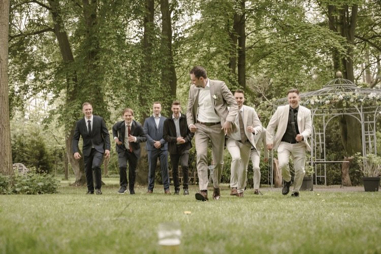Freudig laufende Trauzeugen und Freunde auf einer Wiese